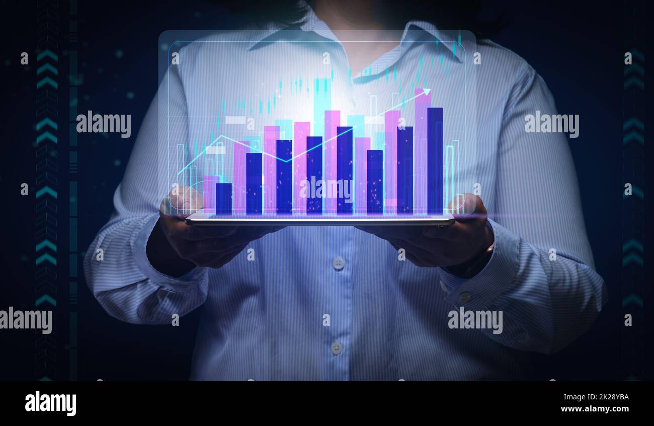 una donna in una camicia a righe può contenere un tablet con una carta olografica virtuale su sfondo blu scuro. Concetto di crescita delle prestazioni, business di successo. crescita del reddito Foto Stock