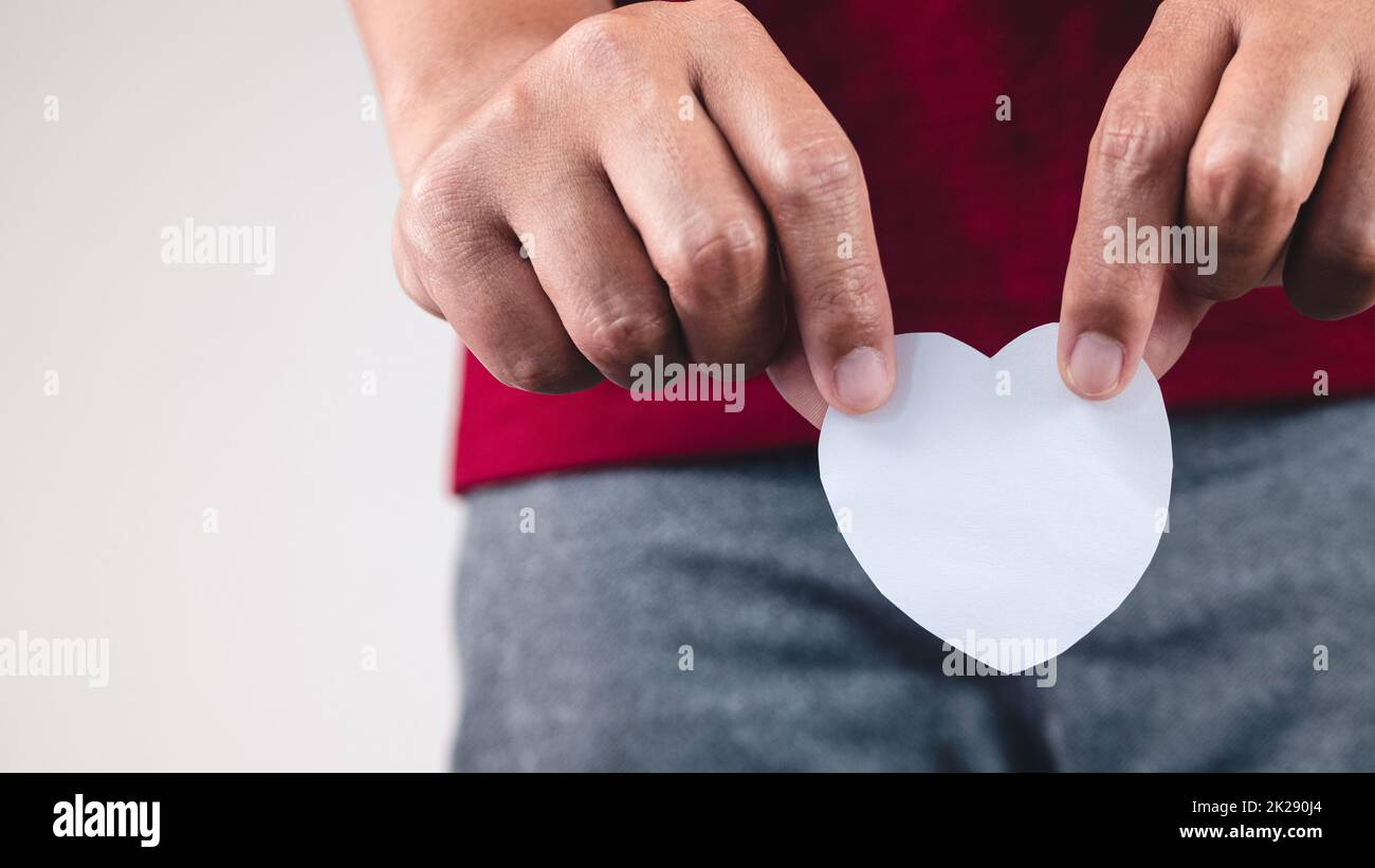 L'uomo mostra un cuore di carta a lato del corpo. Primo piano con spazio per la copia. Foto Stock