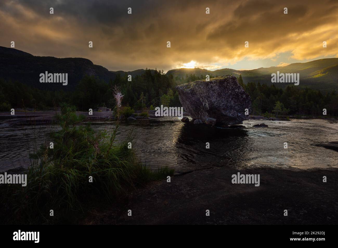 Sosta per il viaggio su strada, grande Boulder nel paesaggio scandinavo del fiume Otra all'alba, Valle Norvegia Foto Stock