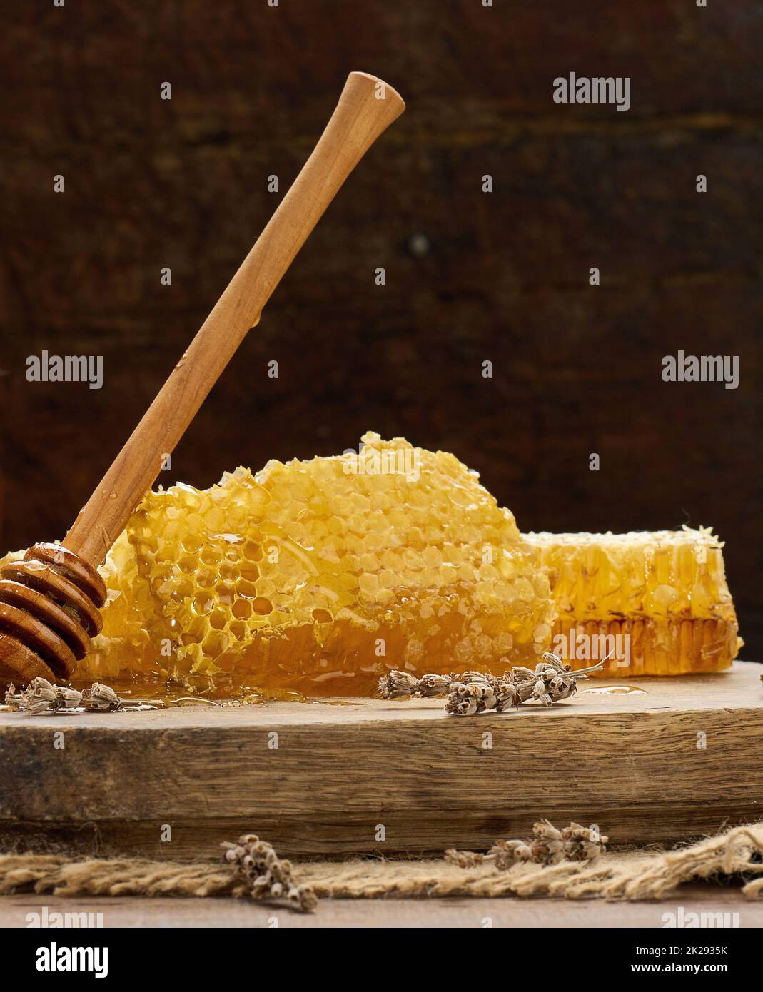 nido d'ape in cera con miele su tavola di legno e cucchiaio di legno, tavola marrone Foto Stock