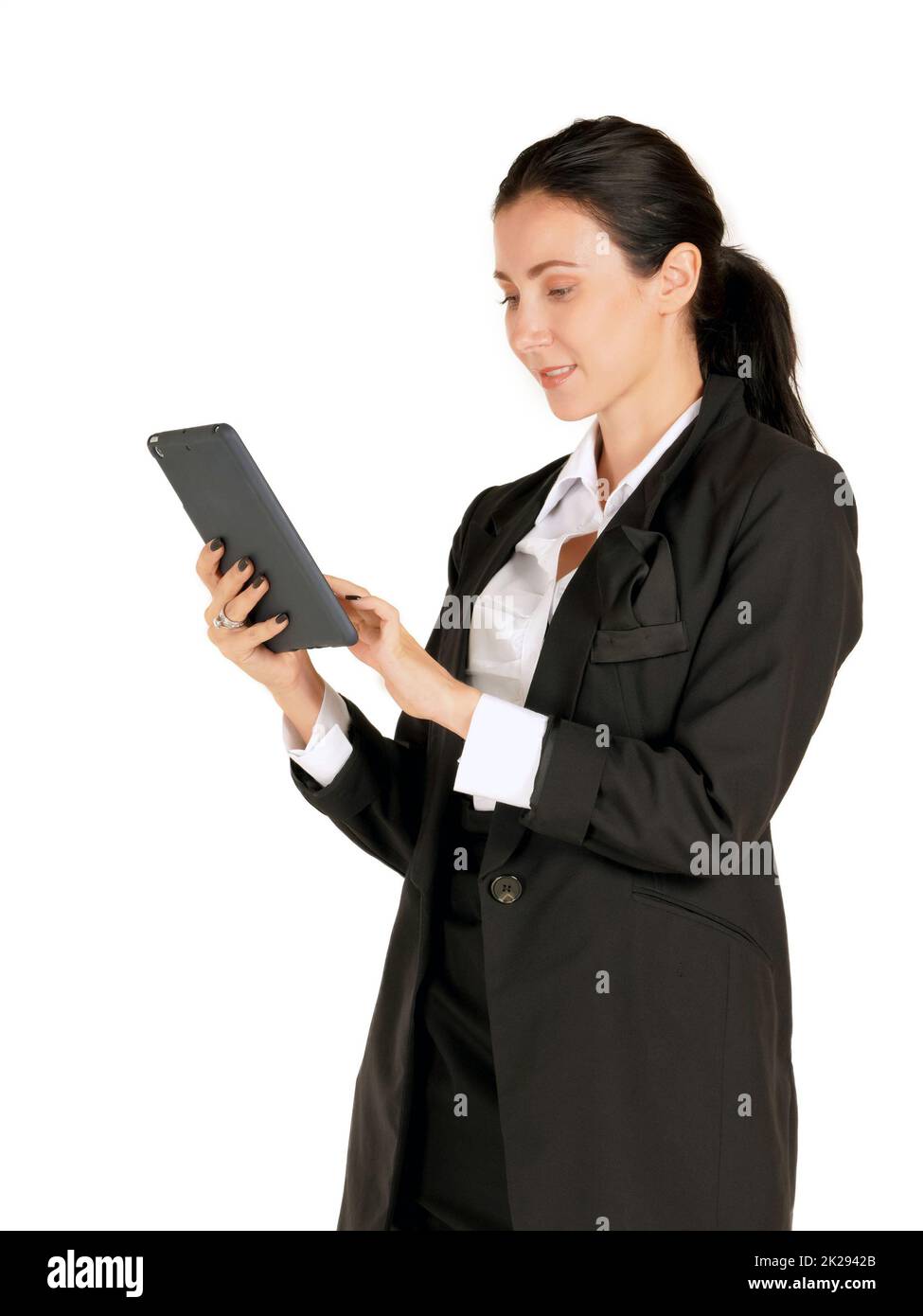 Giovane donna da lavoro caucasica in abito nero con un sorriso, digitando su un computer tablet. Ritratto su sfondo bianco con luce da studio. Foto Stock