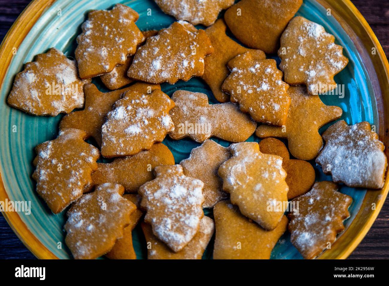 I biscotti sotto forma di alberi di Natale sono sdraiati su una piastra blu primo piano Foto Stock