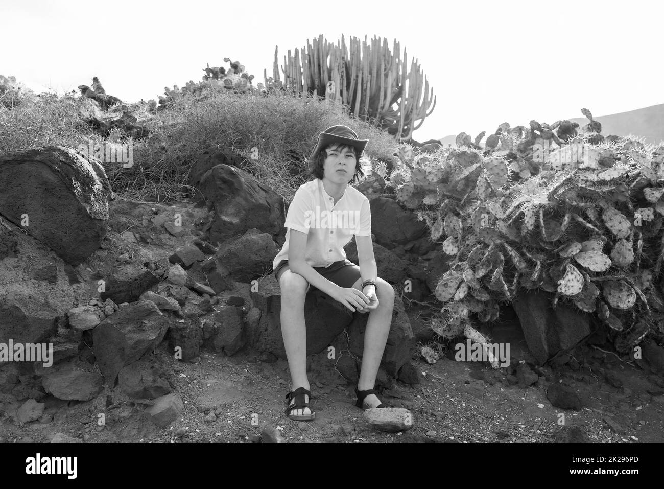 Ritratto di un adolescente in una polo e un cappello sullo sfondo di cactus. Bianco e nero. Foto Stock