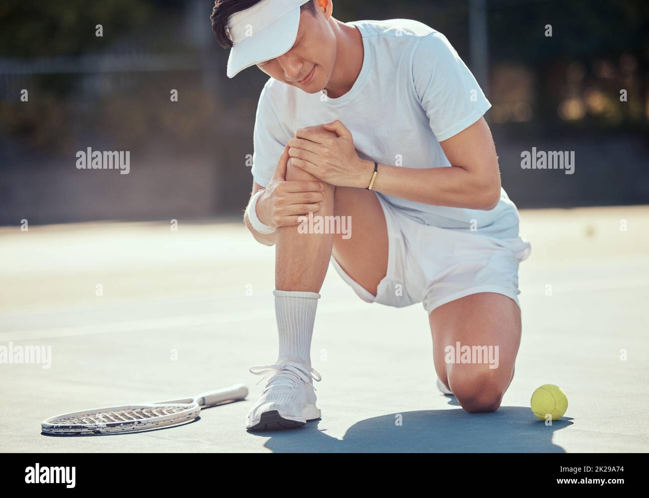 Sport, dolore e lesioni da tennis da parte dell'atleta che tiene il ginocchio durante una partita competitiva in campo all'aperto. Giocatore di tennis asiatico professionista che soffre di Foto Stock