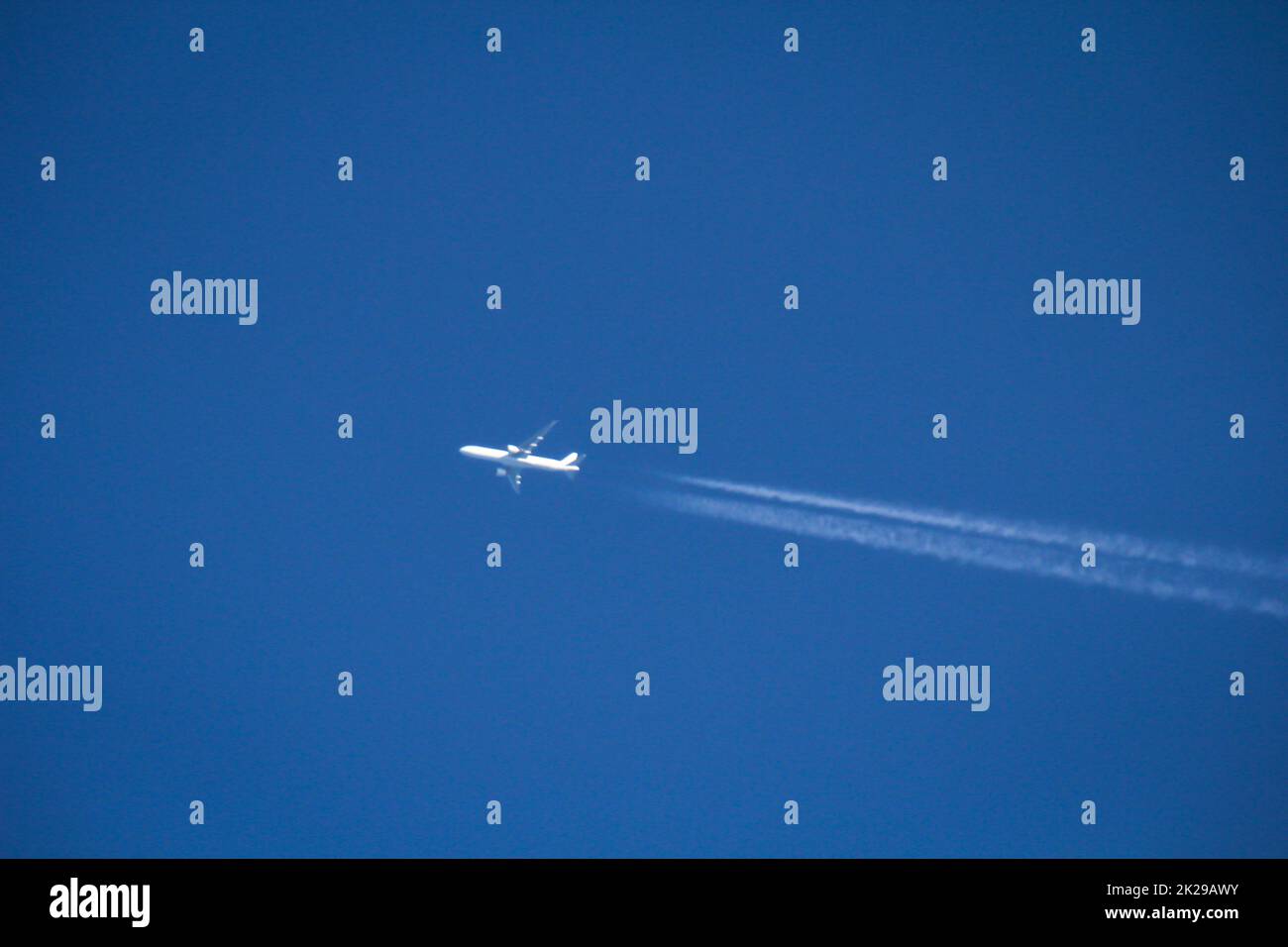 Un jet plane, un aereo passeggeri trascina dietro di esso le strisce di costanza. Foto Stock