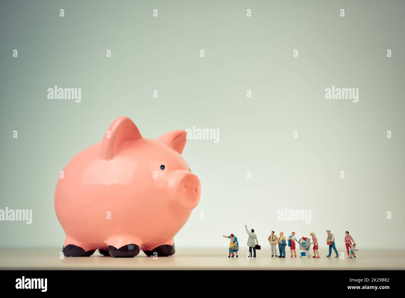 Persone in miniatura e le gigantesche salvadanaio. Famiglia il concetto di bilancio Foto Stock