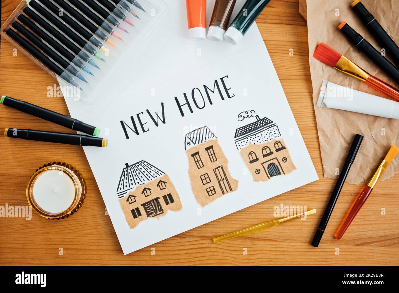 Sognare una nuova casa. Disegno di diverse case testo nuova casa su tavola con pitture, pennelli e cancelleria, forniture per il disegno e artigianato Foto Stock
