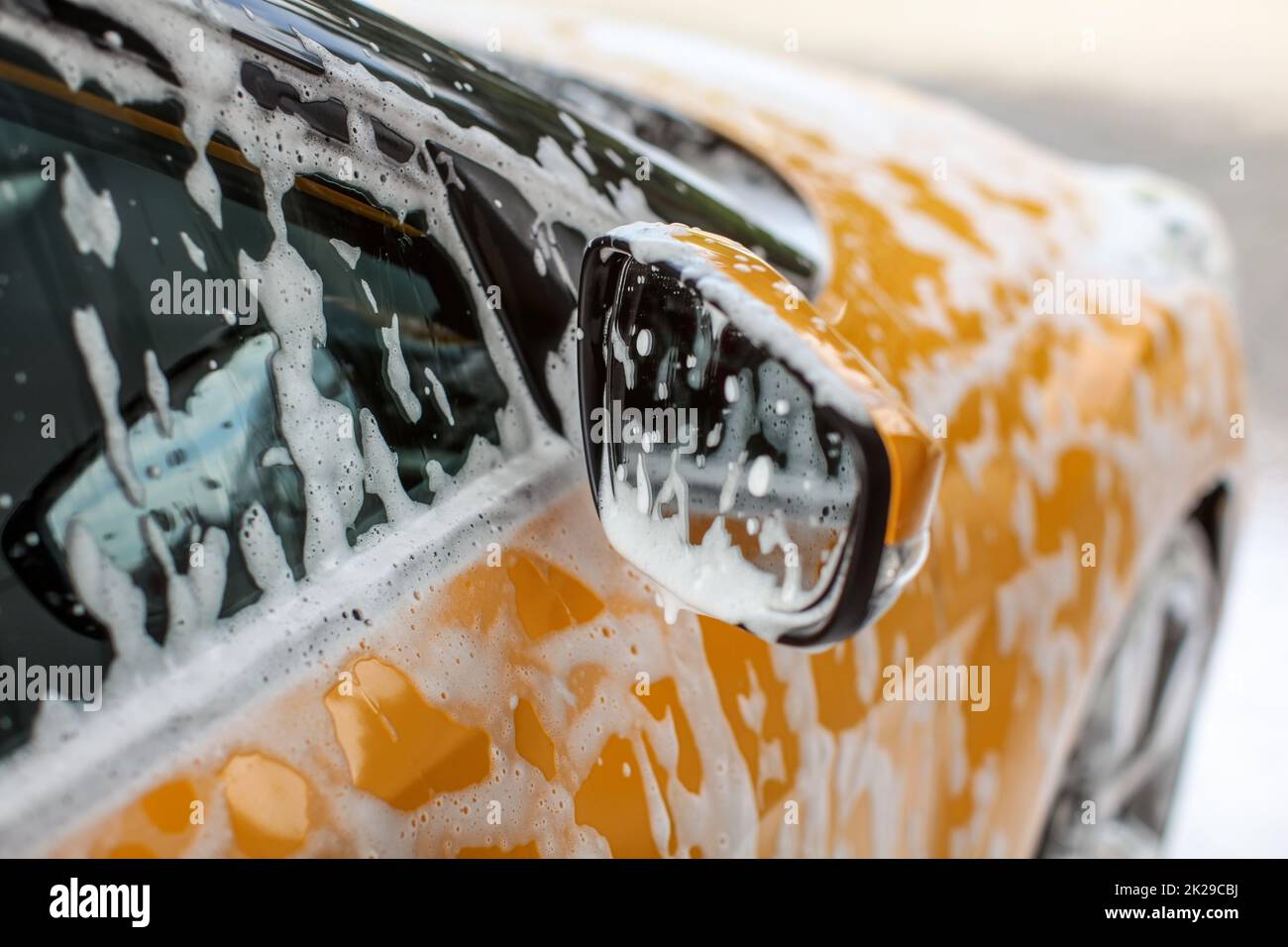 Dettagli su giallo auto specchio laterale, coperto con shampoo e macchie di schiuma, quando lavato in autolavaggi. Foto Stock