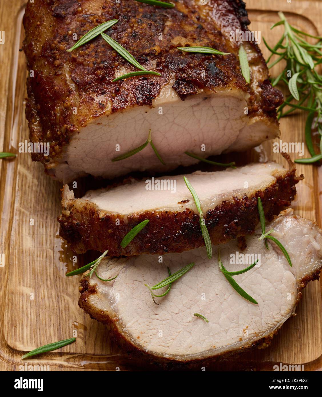 pezzo di carne di maiale al forno in spezie su un asse di legno, tagliato a pezzi. Occhio di bistecca arrosto rotonda Foto Stock