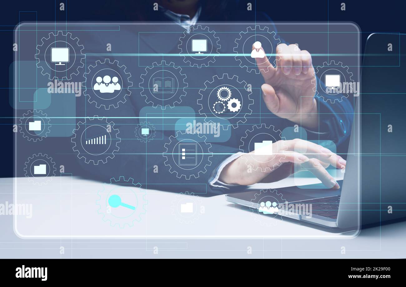 una donna si siede a un tavolo e lavora su un laptop e un ologramma virtuale con icone analitiche nel business. Concetto di analisi dei processi, gestione efficiente Foto Stock