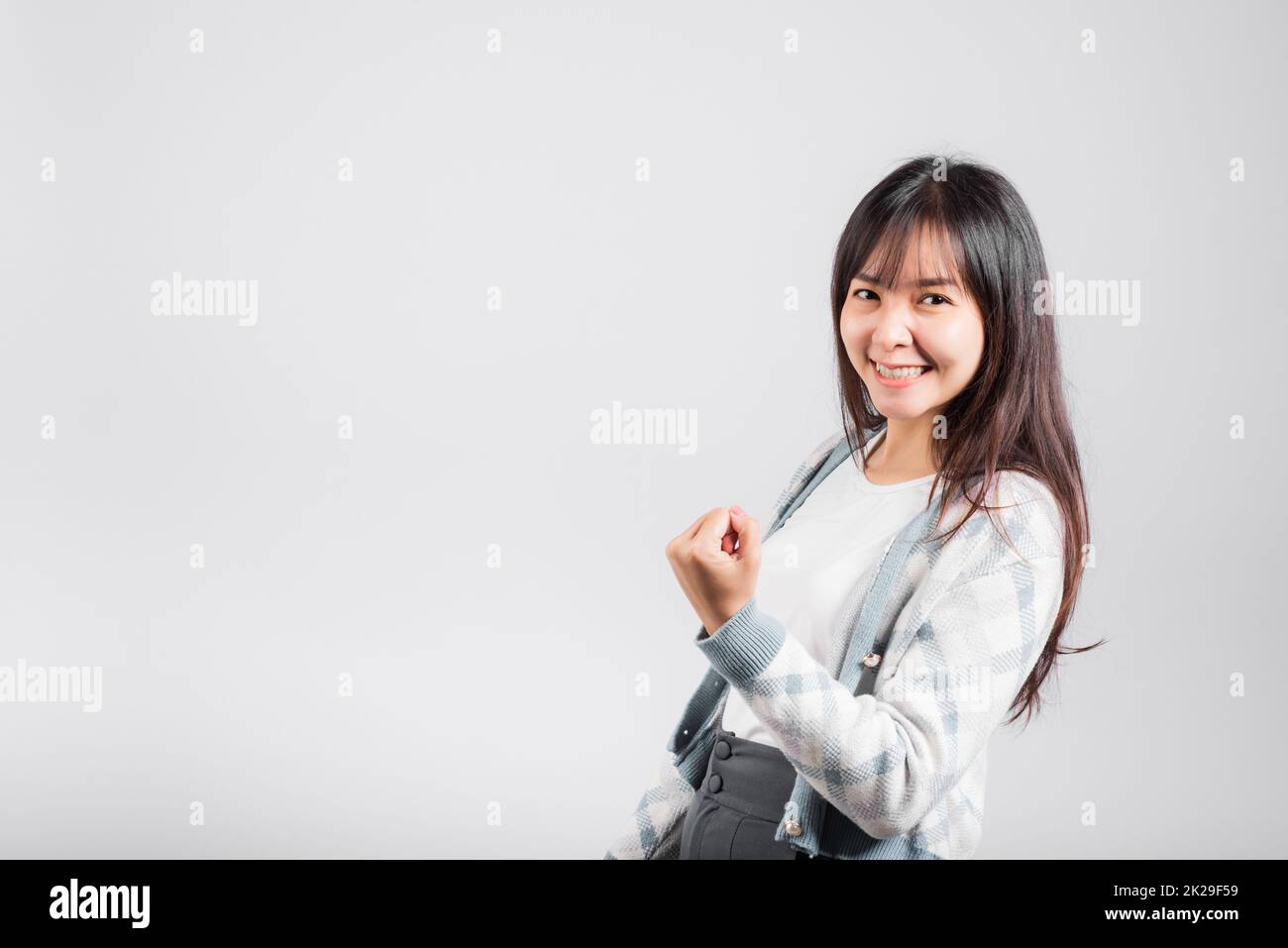 Sorridente donna felice fa pugni alzati in su celebrando il suo gesto di successo di vincita Foto Stock