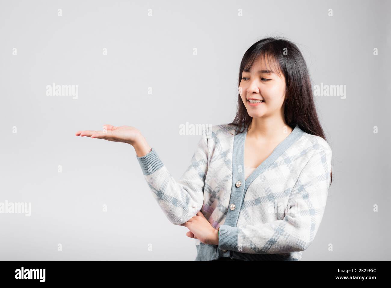 Donna sorridente felice che presenta il prodotto che tiene qualcosa sul lato di palmo via Foto Stock