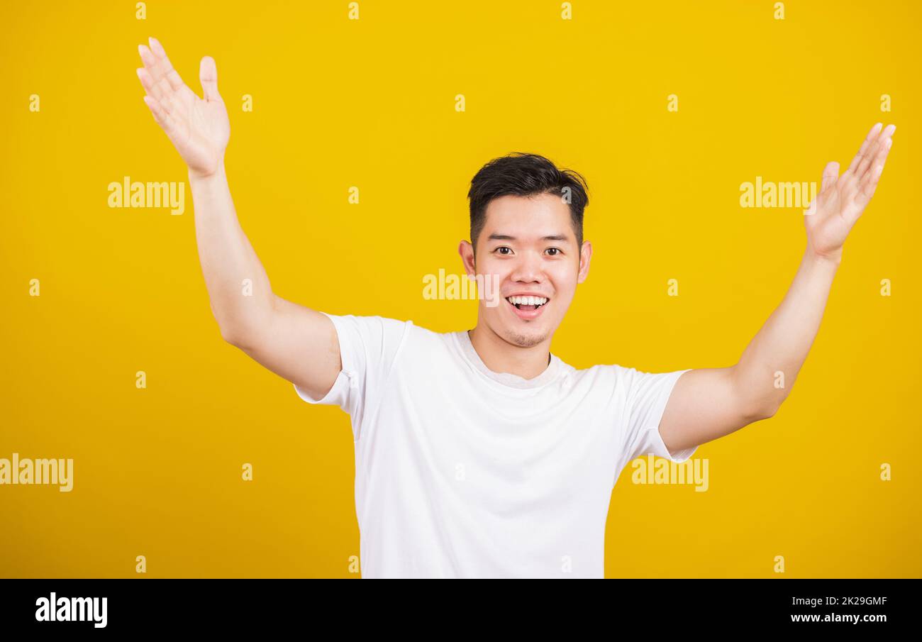 il giovane uomo sorride positivo scuotendo le mani entusiasta gridando sì per vincere la concorrenza Foto Stock