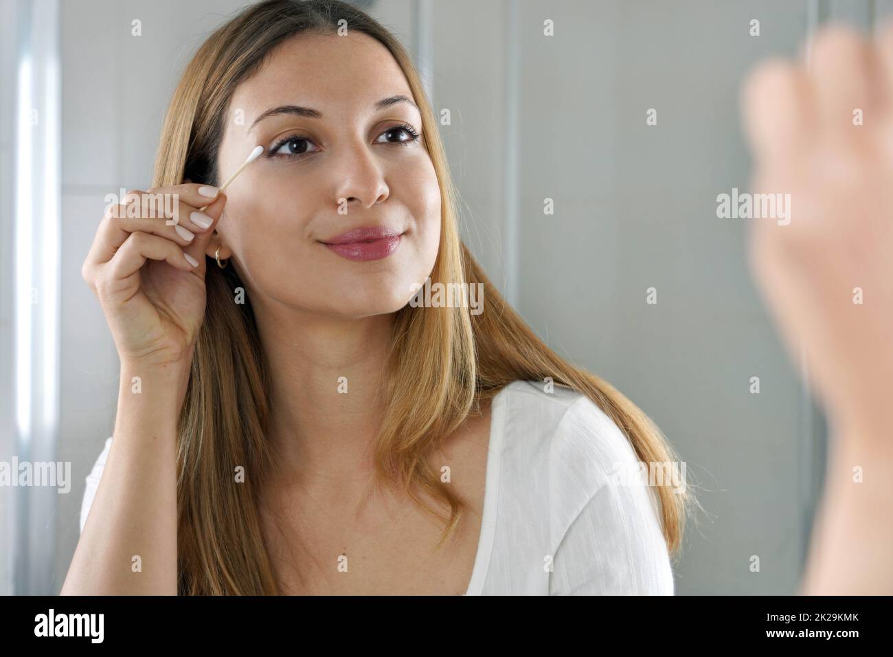 Ritratto di giovane donna utilizzando cotone eco-friendly gemma per rimuovere macchie di trucco Foto Stock