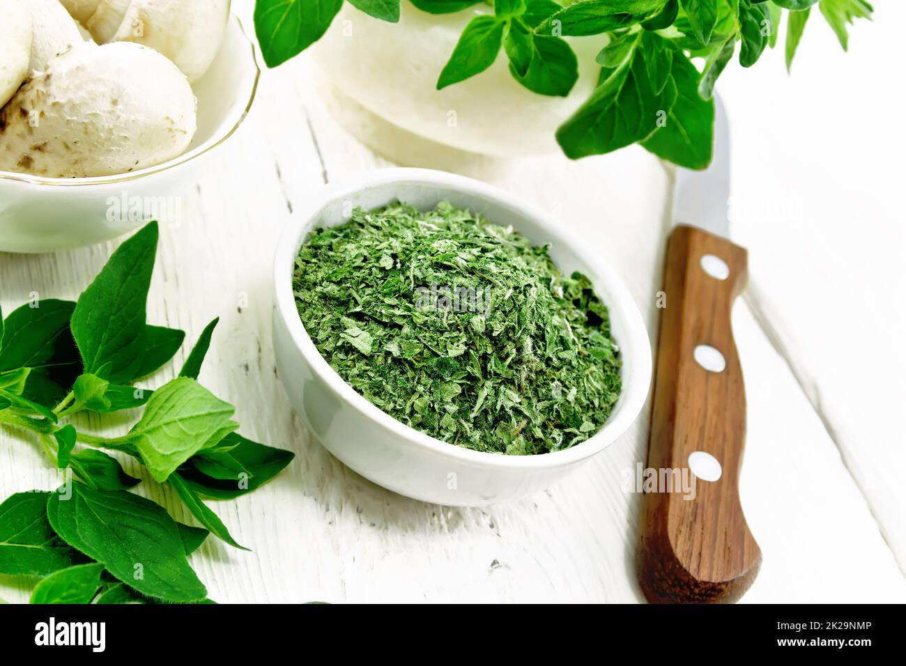 Origano essiccato in ciotola su tavola di legno Foto Stock