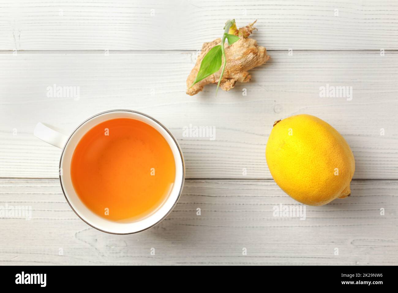 Vista del piano portapaziente, bianco bicchiere di fresco con infuso di tè allo zenzero, limone sul lato, radice secca con il germoglio verde di cui sopra. Foto Stock
