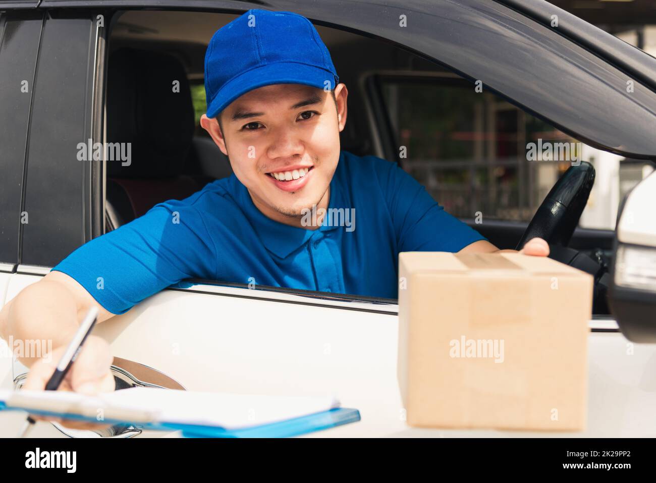 consegna uomo corriere indossare uniforme in auto tenere i documenti clipboard consegna al cliente per la firma Foto Stock