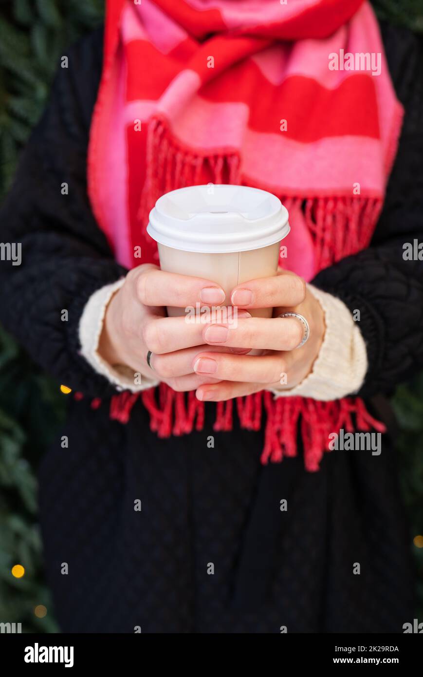 Una giovane ragazza in un cappotto e una sciarpa brillante tiene il caffè  caldo nelle sue mani in una tazza usa e getta. Caffè da andare, escursioni  Foto stock - Alamy