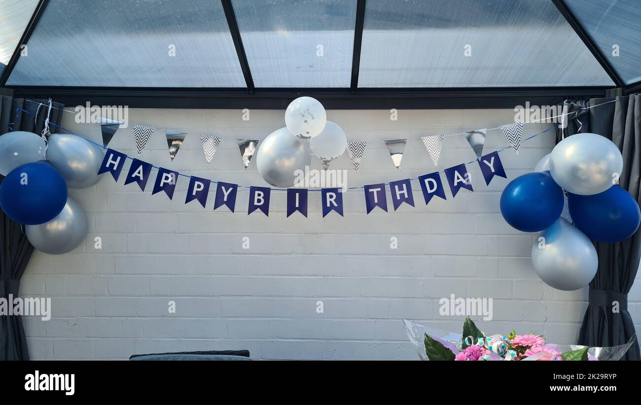 Buon compleanno decorazione appende di fronte a una parete bianca Foto Stock
