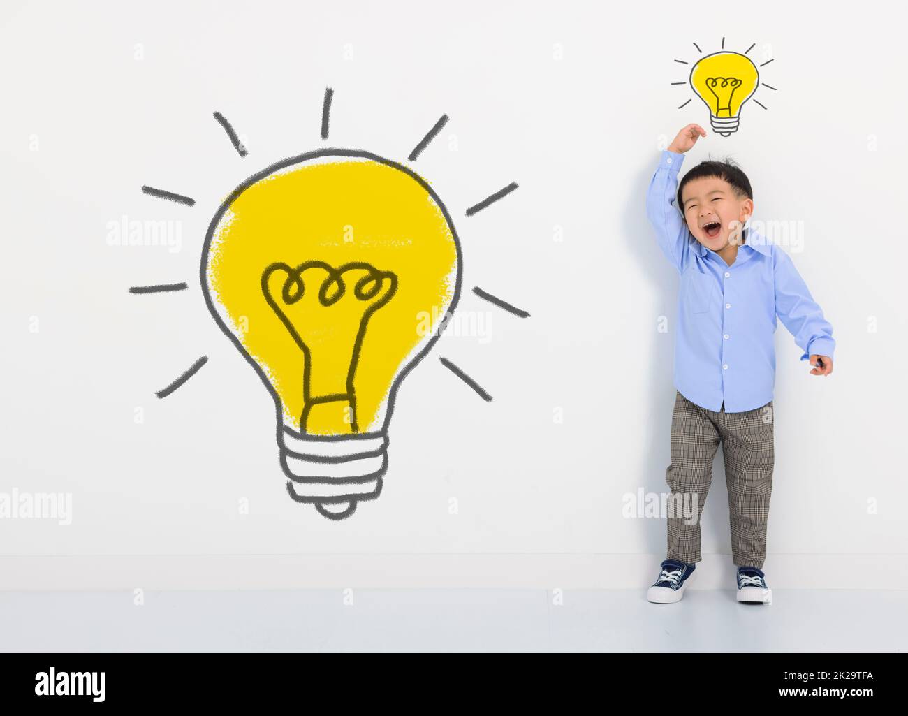 Bambino studente pensiero e lampadina sulla parete bianca . Il ragazzo piccolo carino ha una nuova idea. Tecnologia di innovazione e concetto di istruzione Foto Stock