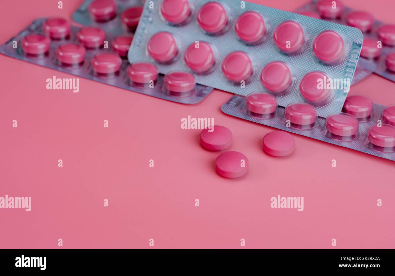 Compresse rosa e blister di pillole su sfondo rosa. Farmaco da prescrizione. Vitamine, minerali, e concetto di supplementi. Industria farmaceutica. Sanità e medicina. Prodotto farmaceutico. Foto Stock