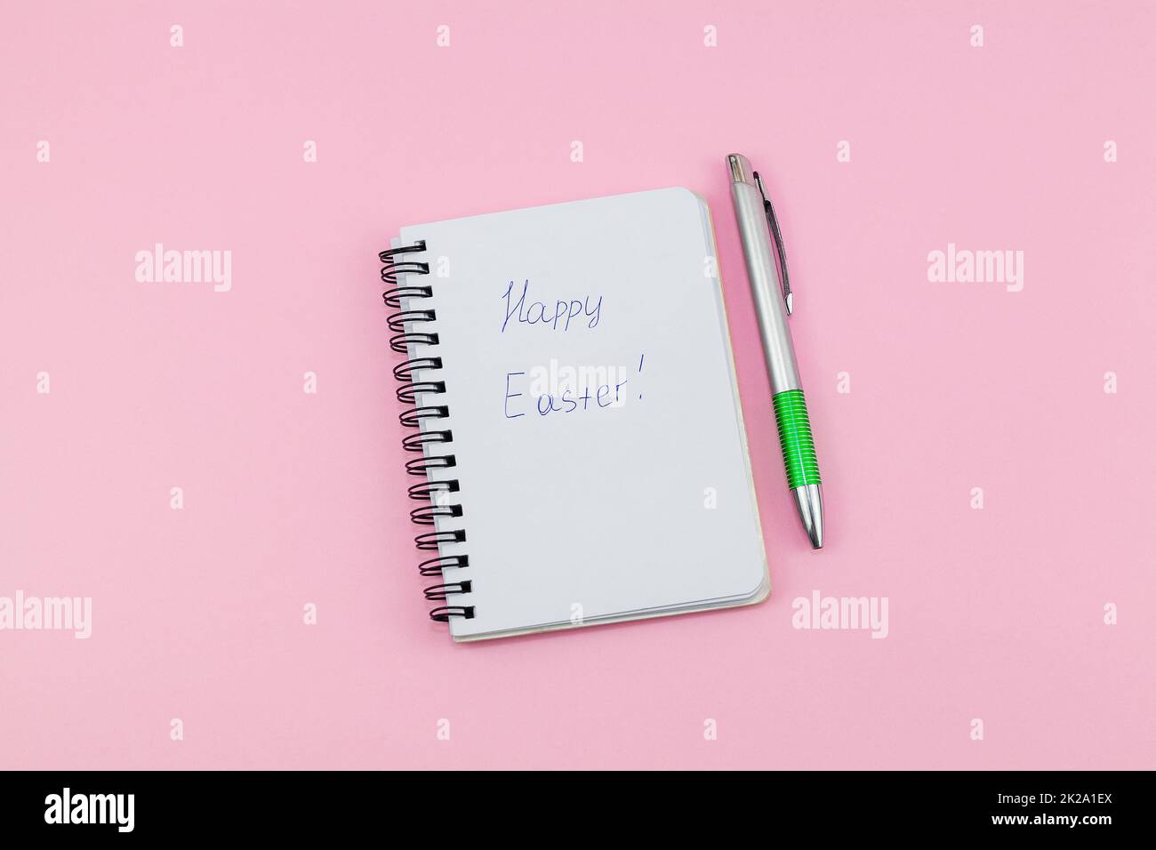 Blocco note e penna su sfondo rosa. Notebook per messaggi di idee, elenco e ispirazione. Scrittura buona Pasqua Foto Stock