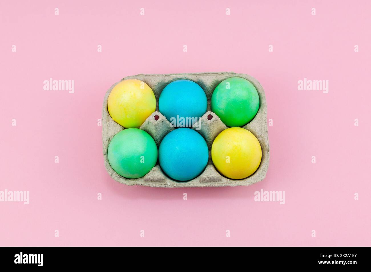 Scatola con colorate uova di Pasqua su sfondo rosa Foto Stock