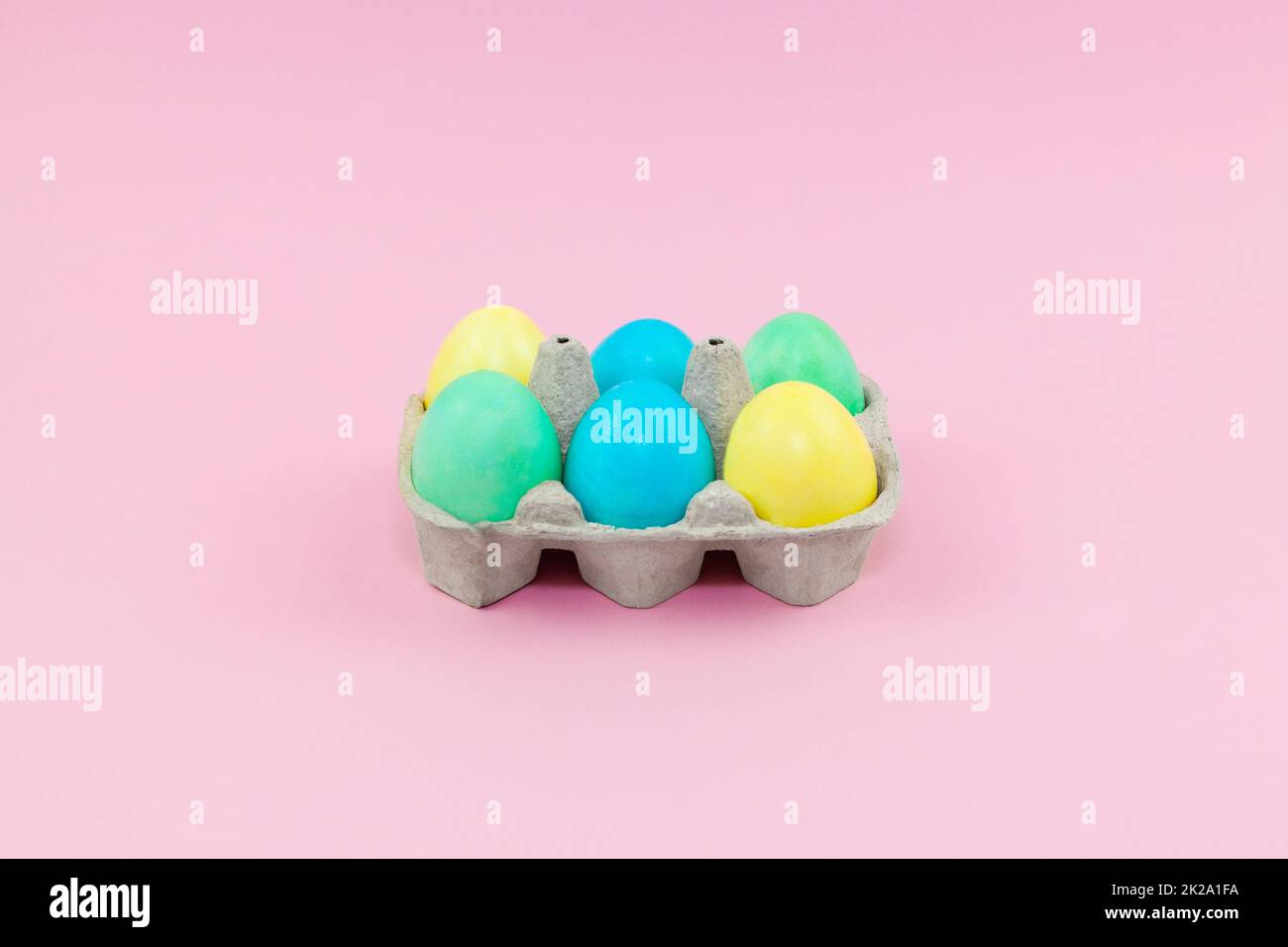Scatola con colorate uova di Pasqua su sfondo rosa Foto Stock