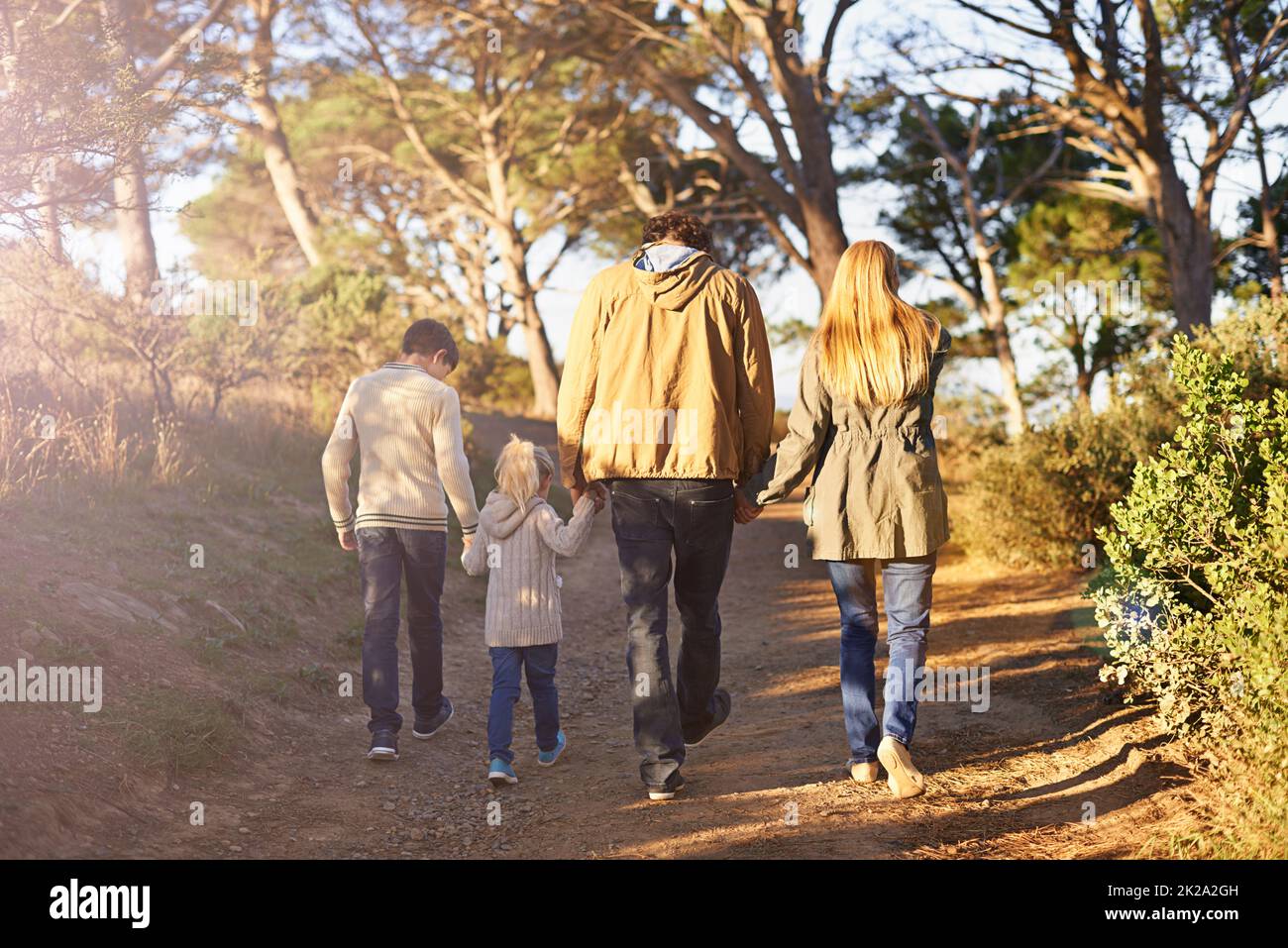 È il momento di un'avventura in famiglia. Foto retrostanti di una giovane famiglia che cammina lungo un sentiero forestale. Foto Stock