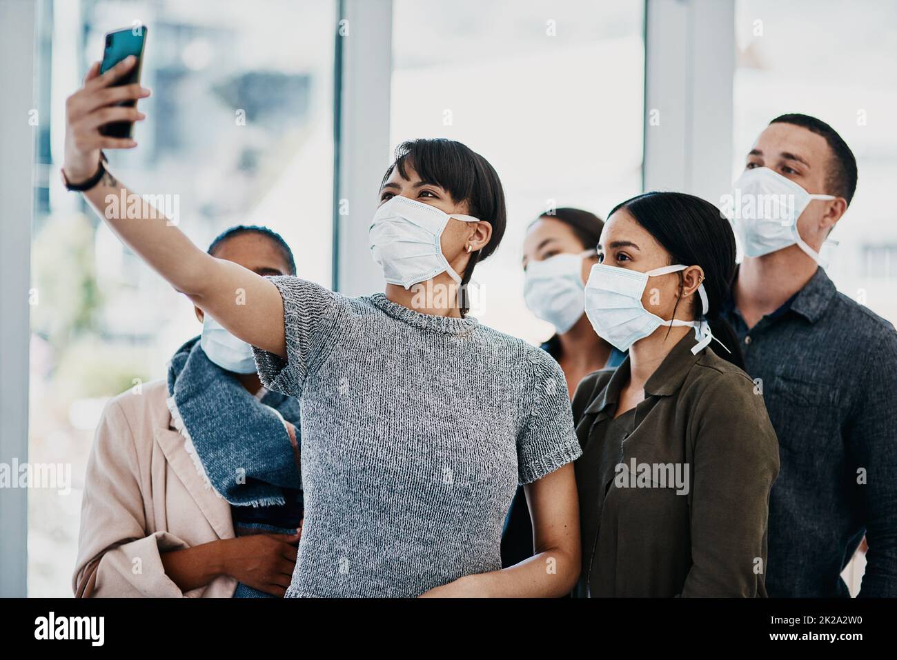 Non lasciate che corona compromesso il vostro cameratismo. Girato di un gruppo di giovani che indossano maschere e prendono selfie all'aeroporto. Foto Stock