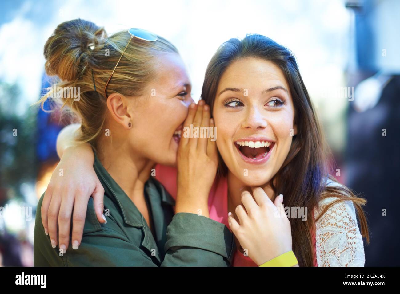 Non ci credo. Una giovane donna sussurra un segreto nell'orecchio dei suoi amici. Foto Stock