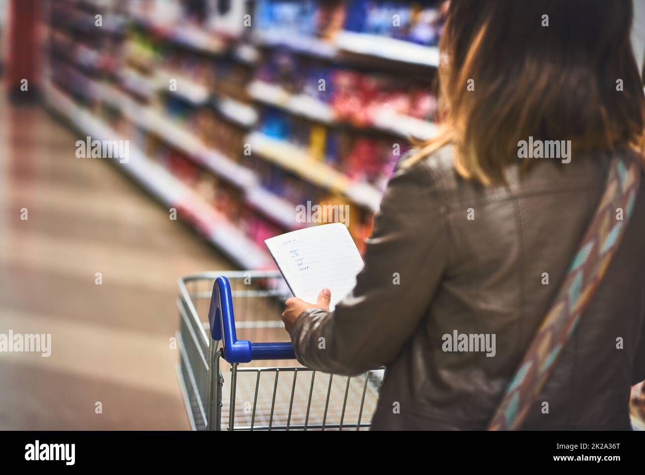 Il pro al negozio di alimentari. Scatto ritagliato di una donna che acquista con una lista in un negozio di alimentari. Foto Stock