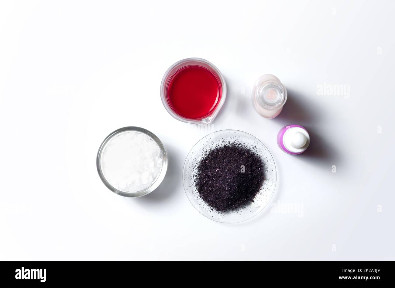 Ingrediente chimico cosmetico su tavola bianca da laboratorio. Cera microcristallina, permanganato di potassio liquido, KMnO4 posto accanto alla crema di bellezza e siero viso. Vista dall'alto Foto Stock