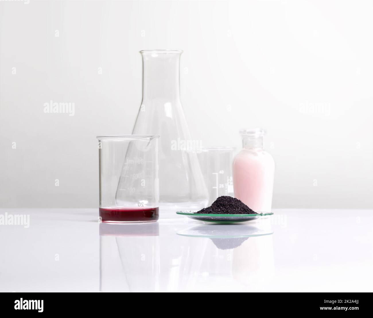 Ingrediente chimico cosmetico su tavola bianca da laboratorio. Liquido di permanganato di potassio, KMnO4 ml, crema di bellezza da collocare accanto al bicchiere e al matraccio di erlenmeyer. Foto Stock