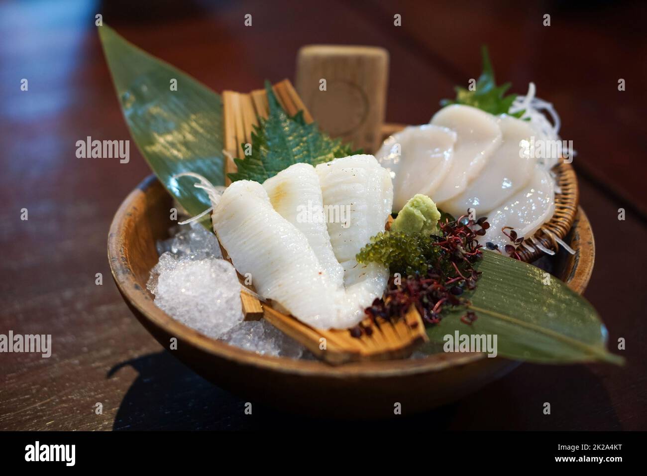 Il set sashimi è ben organizzato in un piatto di legno decorato con foglie di bambù verde. Buffet di cucina Giapponese. Scelta dello chef: Engawa, caldo Foto Stock