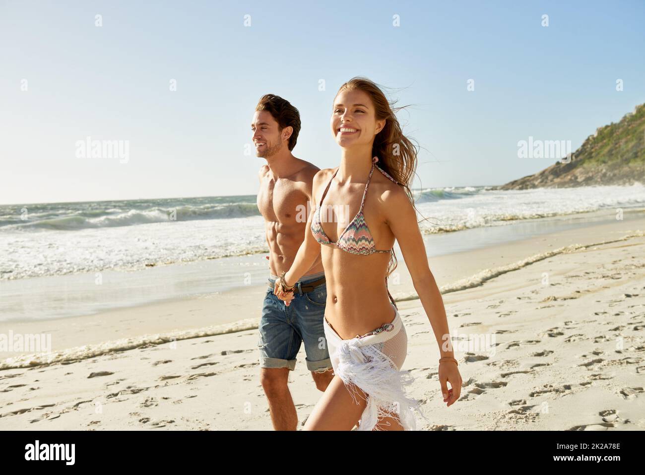 Buon giorno in spiaggia. Scatto di una giovane coppia romantica che cammina a mano sulla spiaggia. Foto Stock