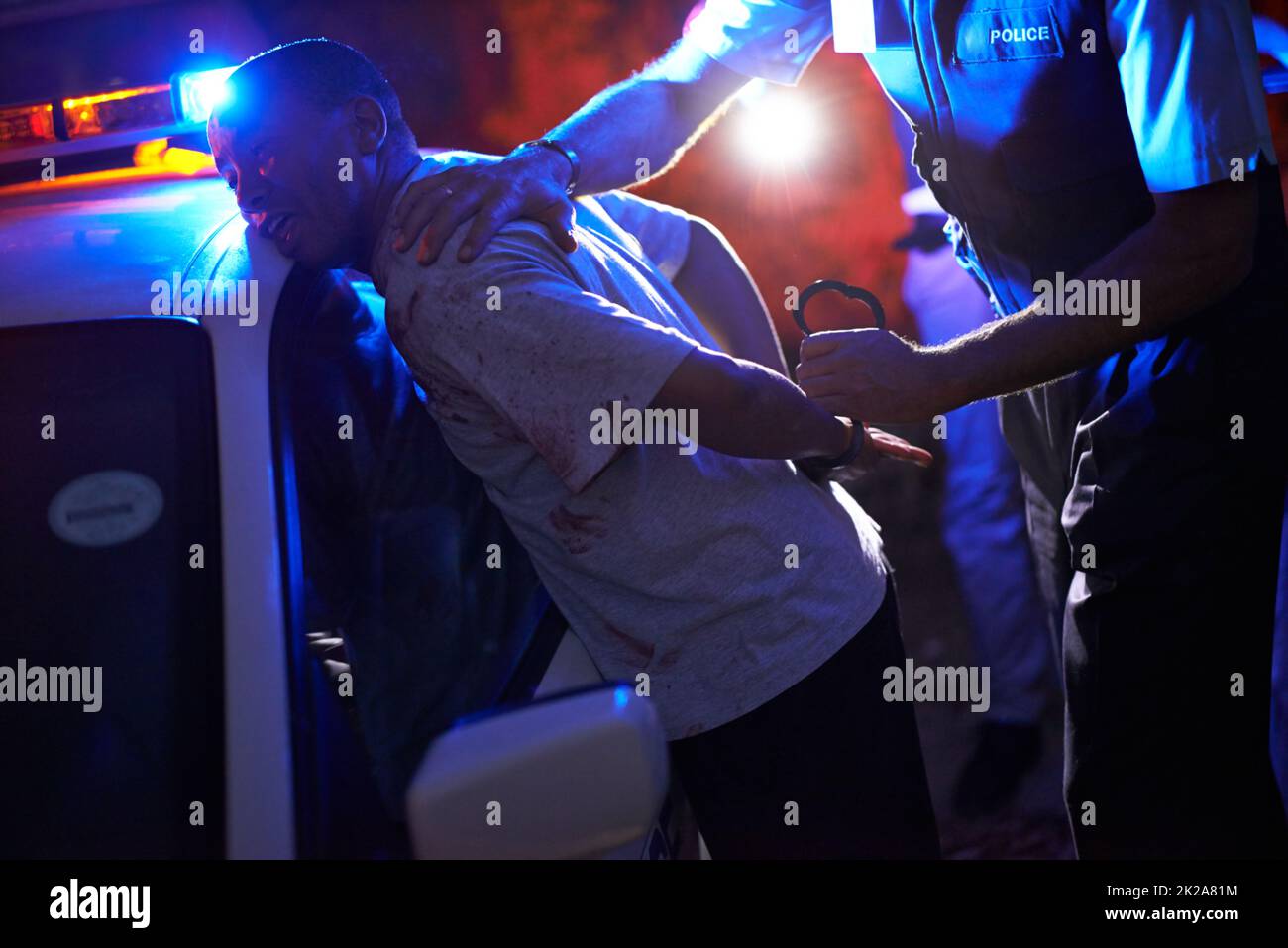 Servire e proteggere. Colpo di un ufficiale di polizia che manica un sospetto contro la sua macchina di pattuglia. Foto Stock