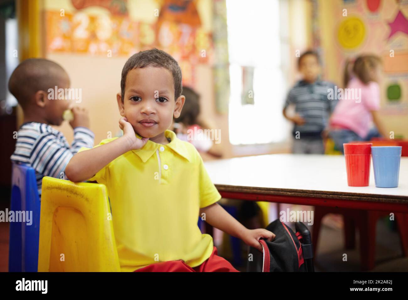 Guardando al futuro con positività. Ritratto di un ragazzo etnico carino in posa per la sua foto al tavolo di una classe pre-scuola. Foto Stock