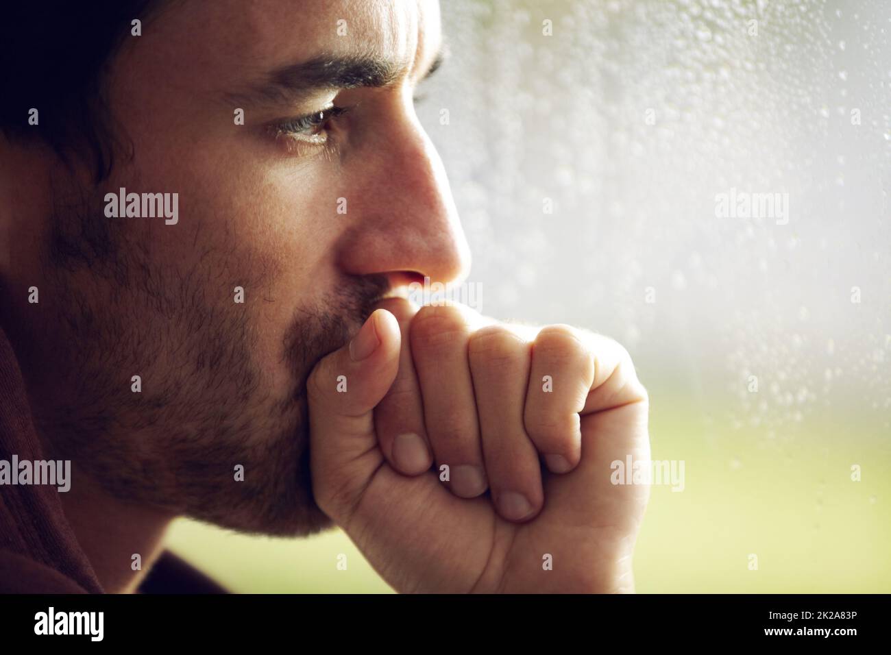 Turbato dai suoi pensieri. Un giovane che guarda pensivo mentre copre la bocca con una mano stringata. Foto Stock