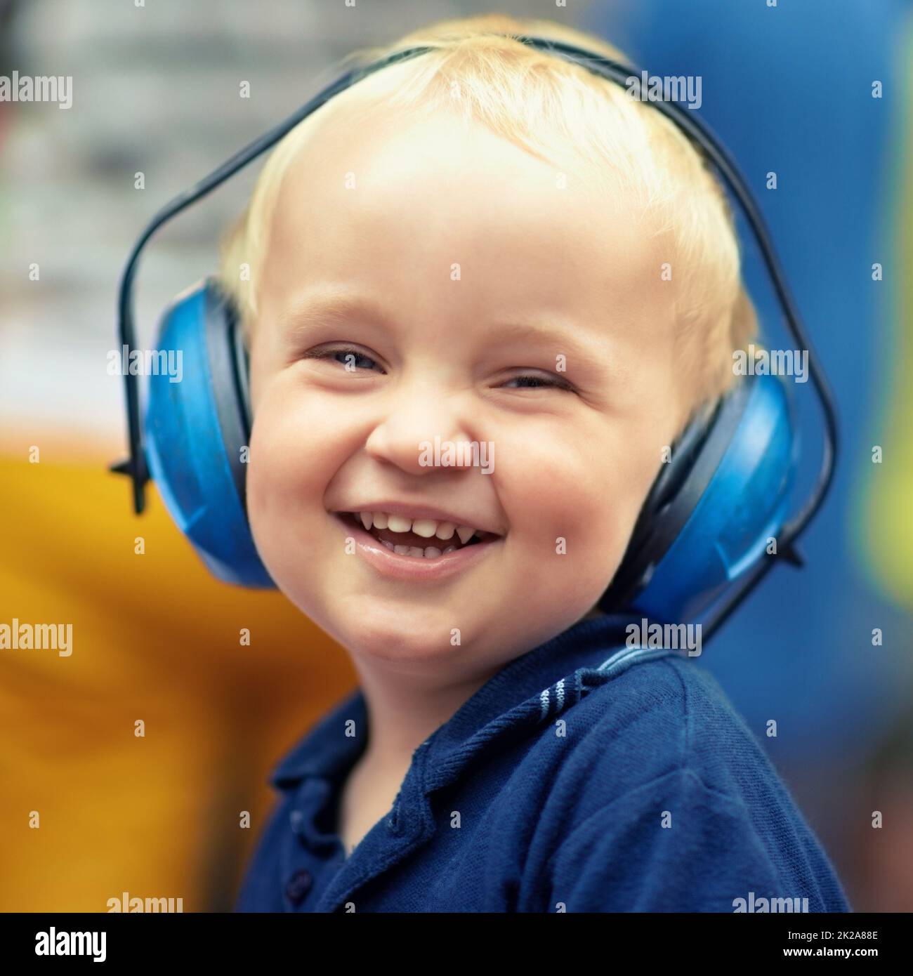 Il momento migliore della sua giovane vita. Ritratto closeup di un ragazzino che ride indossando cuffie protettive in un festival di musica all'aperto. Foto Stock