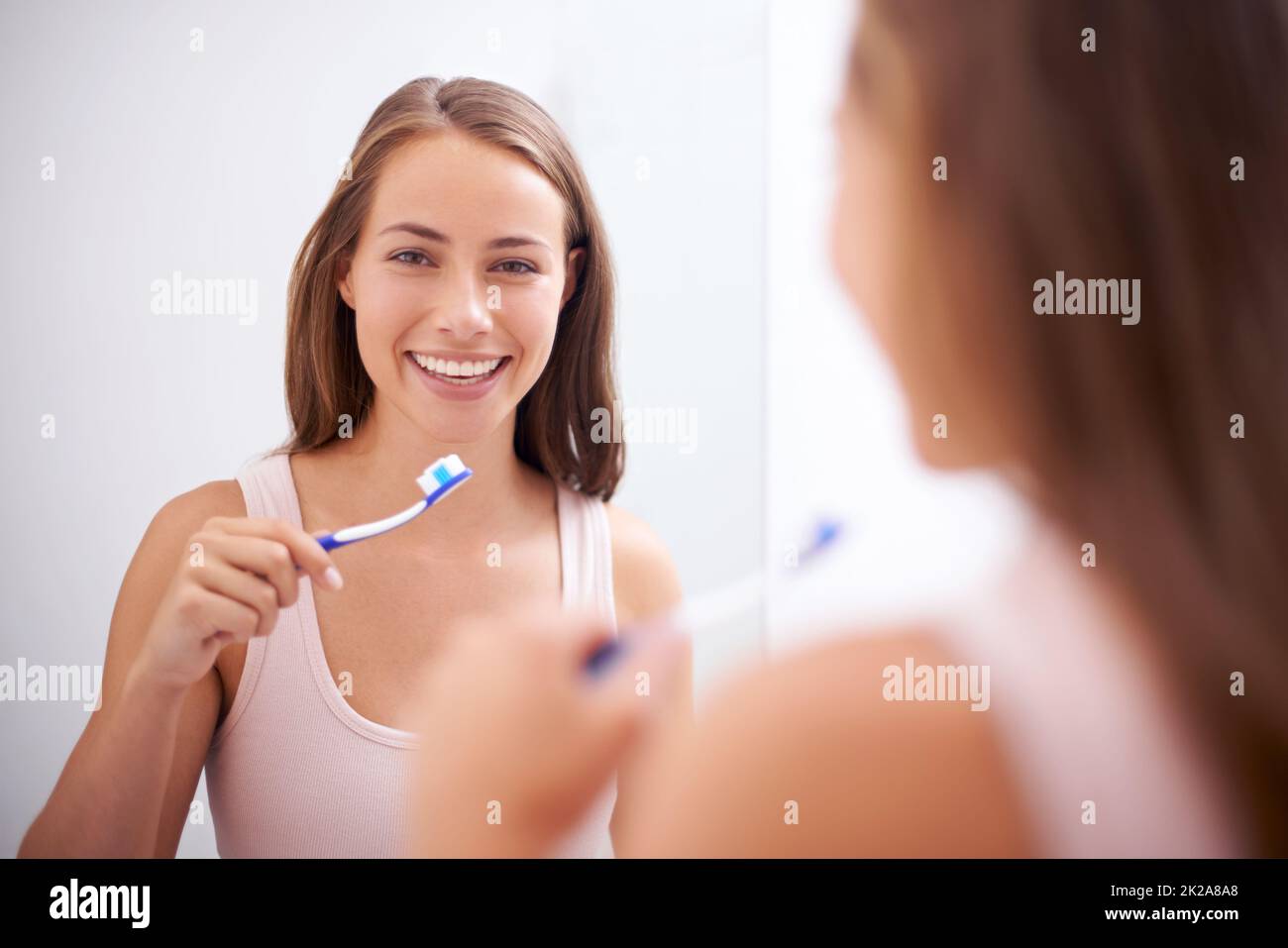 Prendersi cura del suo sorriso. Una giovane donna che le spazzolava i denti. Foto Stock