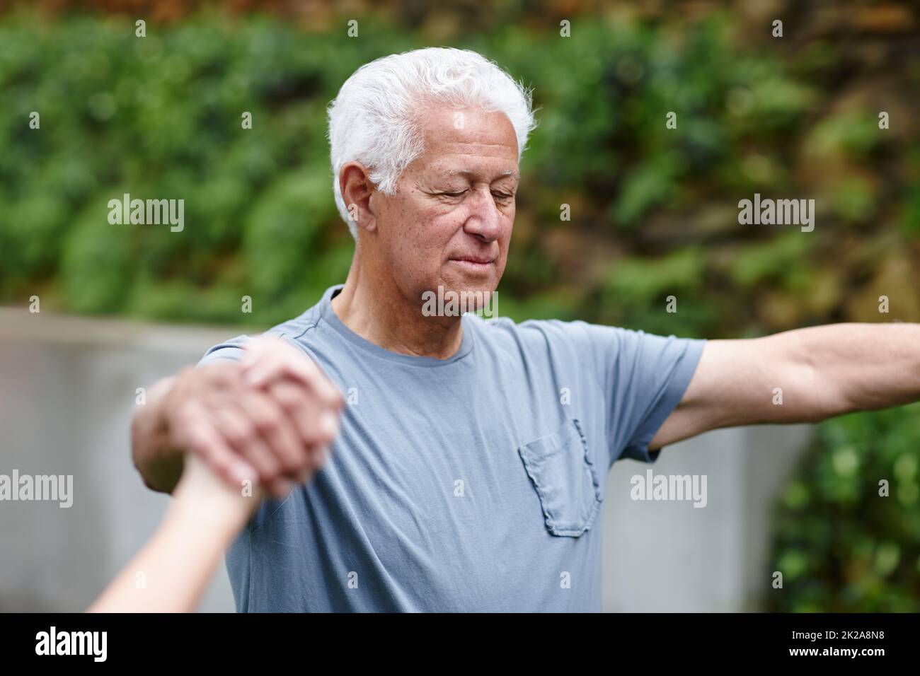 La sua spiritualità è importante per lui. Shot di un uomo anziano che tiene le mani con la gente che fa yoga con. Foto Stock