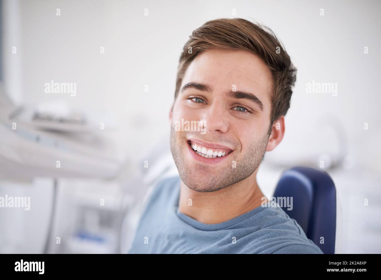 Ogni paziente preferito dai dentisti. Ritratto di un giovane uomo sorridente seduto su una sedia dentista. Foto Stock