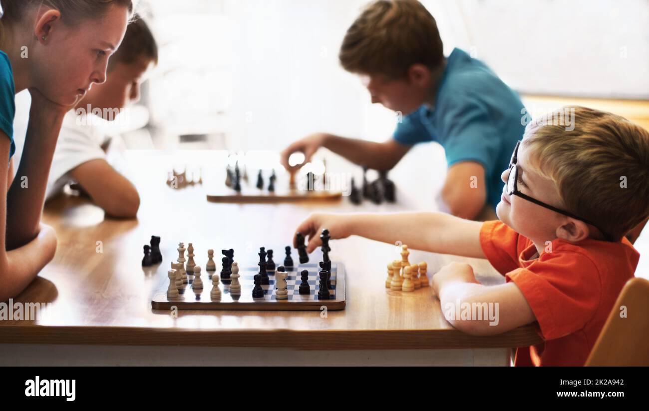 Chess Whiz. Ragazzo giovane che indossa occhiali e gioca a scacchi con un bambino più grande. Foto Stock