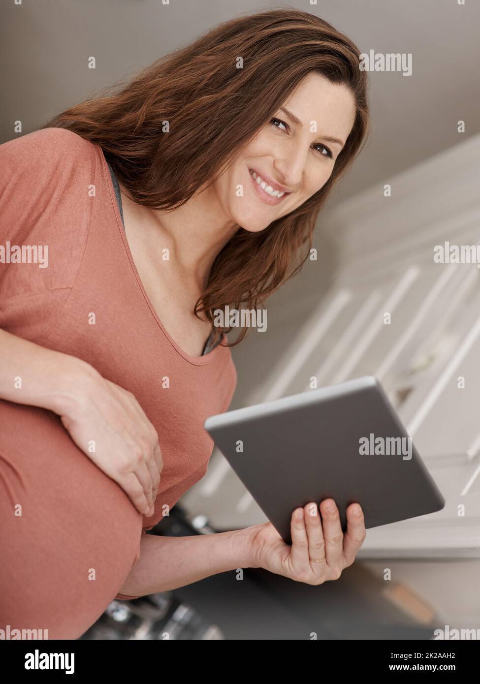 Essere al passo con gli sviluppi prenatali. Ritratto a basso angolo di una donna incinta utilizzando un tablet digitale. Foto Stock