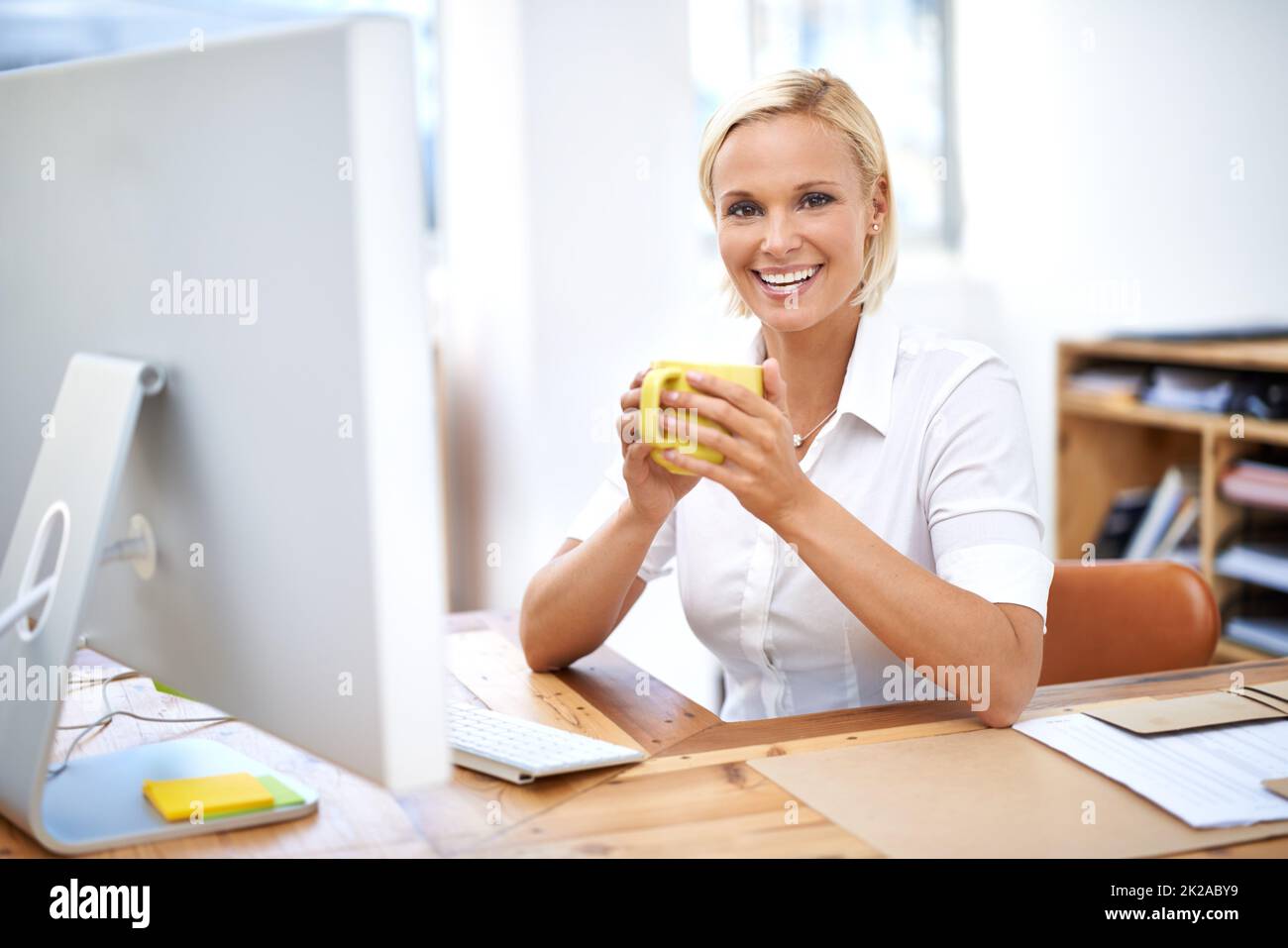 Veloce pausa caffè. Ritratto di una giovane donna d'affari che beve caffè alla sua scrivania. Foto Stock