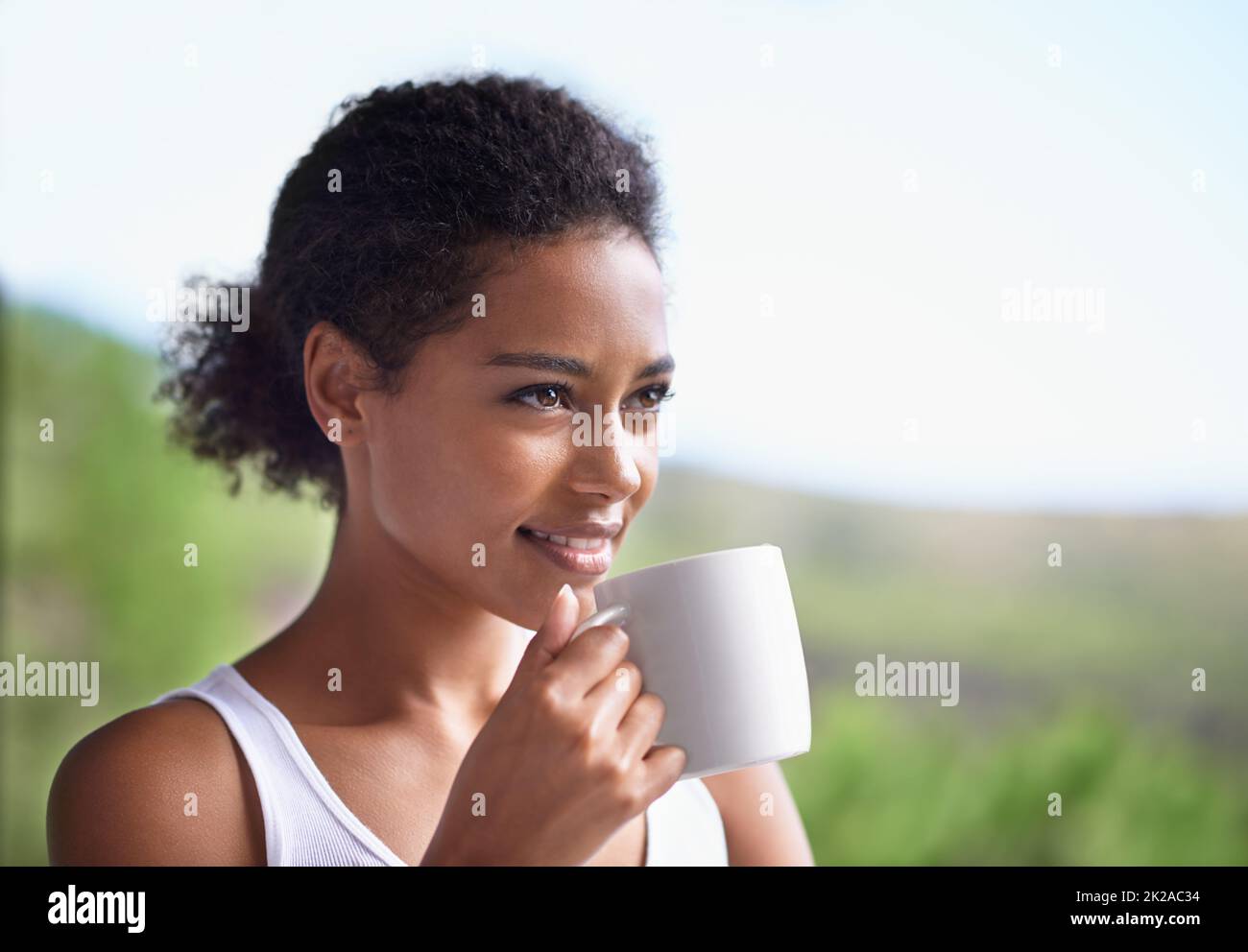 Saluto il sole del mattino con un sorriso. Scatto corto di una giovane donna godendo una tazza di caffè. Foto Stock
