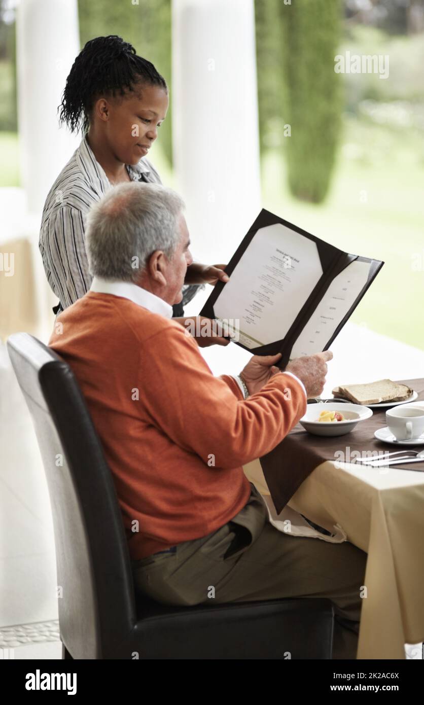 Mostrargli le offerte speciali. Un uomo anziano che è mostrato le specials su un menu dalla sua cameriera. Foto Stock