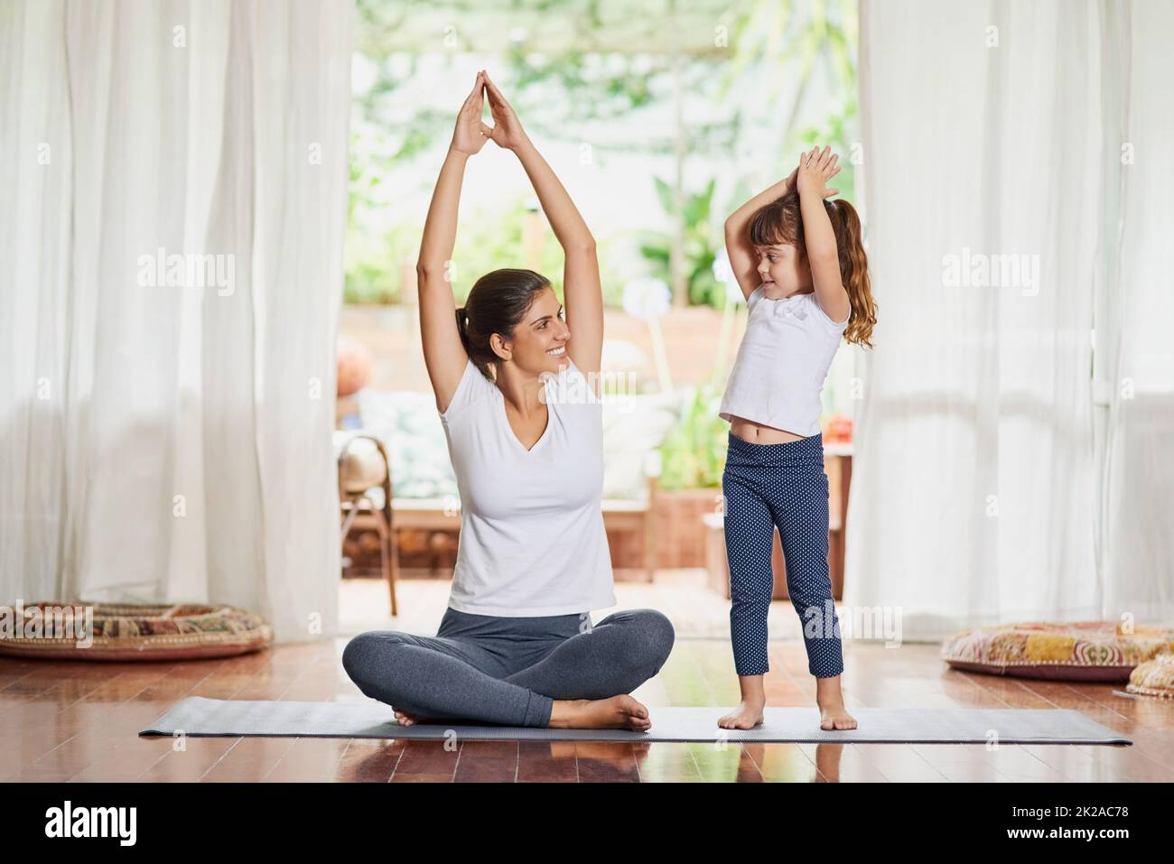 Youre arrivare mio figlio. Shot di una giovane madre e figlia focalizzata che fanno una posa yoga con le loro braccia sollevate sopra la testa. Foto Stock
