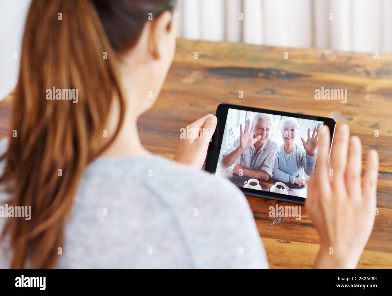 Chiacchierando con la sua gente. Una giovane donna che usa un tablet digitale per una videochiamata con la sua famiglia. Foto Stock